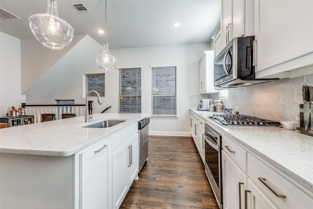 kitchen with appliances with stainless steel finishes, sink, decorative light fixtures, white cabinetry, and an island with sink