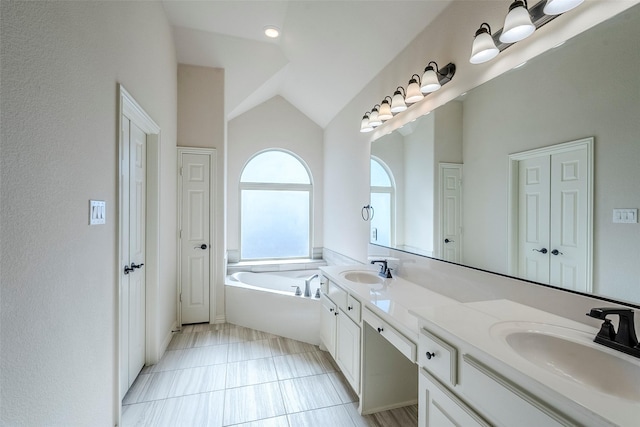 bathroom featuring a washtub, vanity, and lofted ceiling