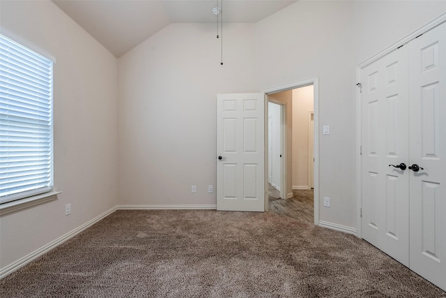 unfurnished bedroom featuring vaulted ceiling, a closet, carpet, and multiple windows