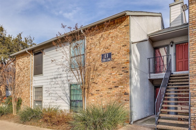 15151 Berry Trl Unit 1104, Dallas, TX 75248 - view of property exterior with stucco siding, brick siding, a chimney, and stairway