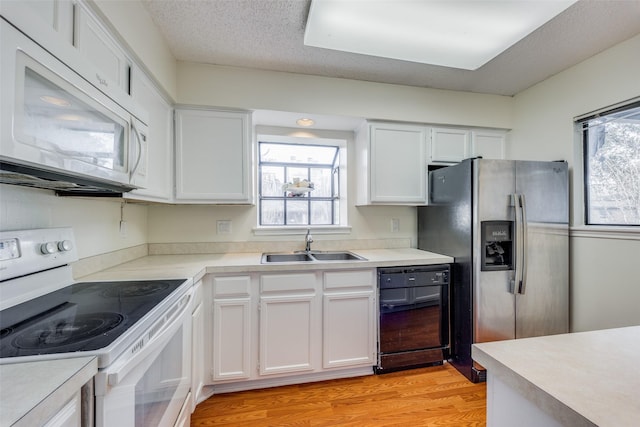 kitchen with white appliances, white cabinets, sink, light wood-type flooring, and a textured ceiling