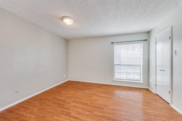 empty room with a textured ceiling and light wood-type flooring