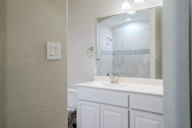 bathroom featuring tiled shower, vanity, and toilet