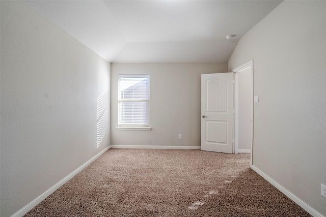 carpeted empty room featuring vaulted ceiling