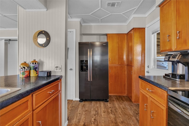 kitchen featuring stainless steel fridge, light hardwood / wood-style flooring, stove, and ornamental molding