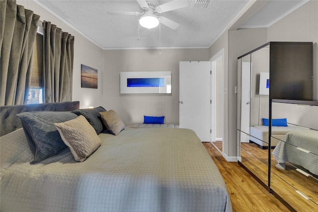 bedroom with hardwood / wood-style flooring, ceiling fan, crown molding, and a textured ceiling