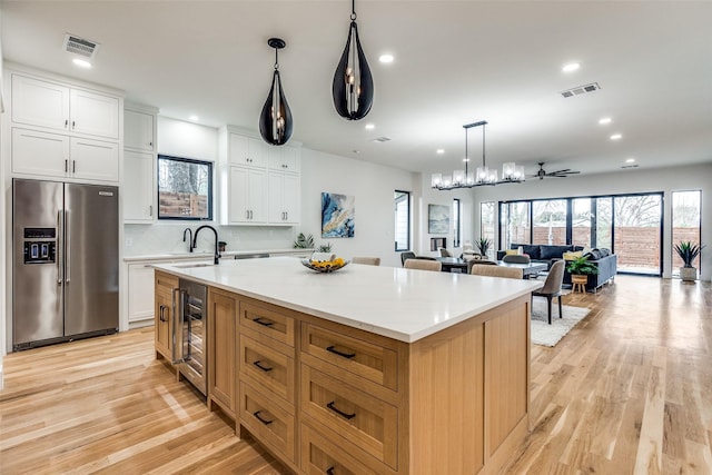 kitchen featuring white cabinetry, sink, beverage cooler, stainless steel fridge, and a spacious island