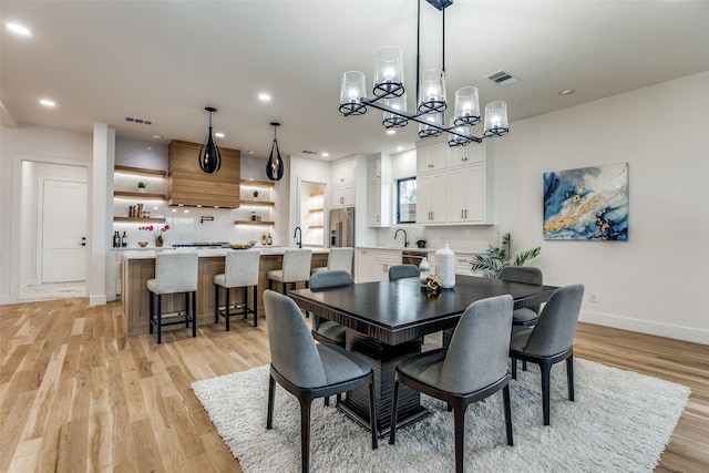 dining area with a chandelier, light hardwood / wood-style floors, and sink