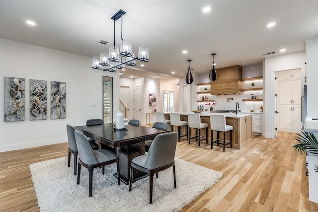 dining space featuring light hardwood / wood-style floors, sink, and a chandelier