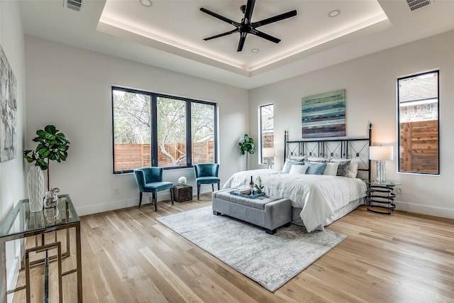 bedroom with a tray ceiling, ceiling fan, and light hardwood / wood-style floors