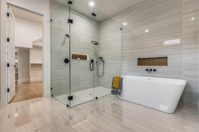 bathroom with tile patterned floors, separate shower and tub, and tile walls