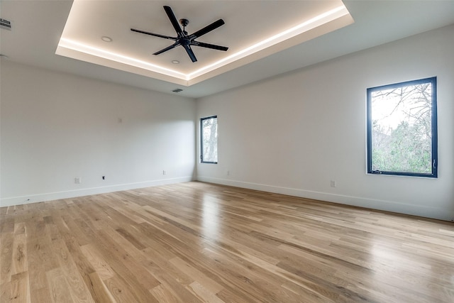 unfurnished room with a tray ceiling, light hardwood / wood-style flooring, and ceiling fan