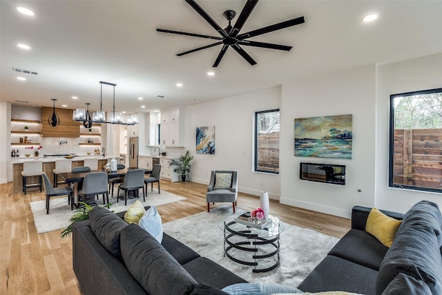 living room featuring ceiling fan, sink, and light hardwood / wood-style flooring