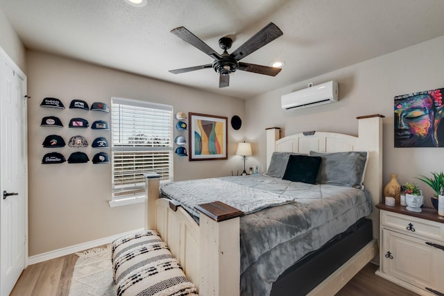 bedroom with a wall mounted air conditioner, ceiling fan, and light wood-type flooring