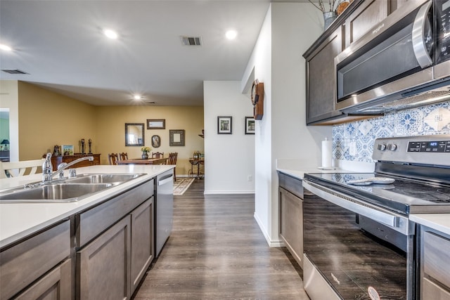 kitchen featuring backsplash, dark brown cabinets, sink, appliances with stainless steel finishes, and dark hardwood / wood-style flooring