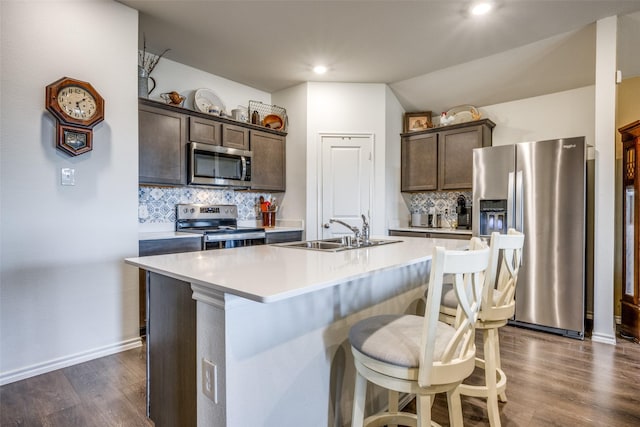 kitchen featuring tasteful backsplash, dark brown cabinets, stainless steel appliances, and an island with sink