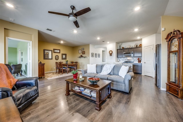 living room featuring ceiling fan and dark hardwood / wood-style floors