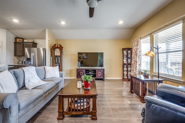 living room with ceiling fan, lofted ceiling, and light hardwood / wood-style floors