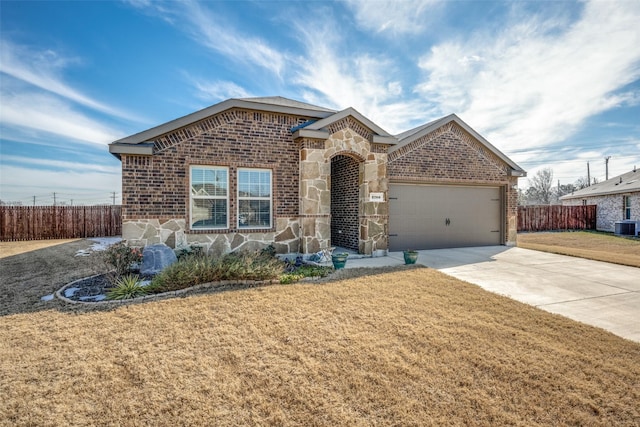 view of front of home featuring a front lawn, a garage, and central air condition unit