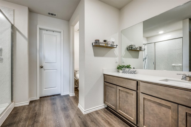 bathroom featuring a shower with shower door, vanity, wood-type flooring, and toilet