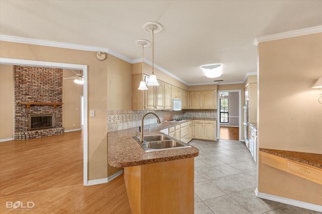 kitchen with sink, a brick fireplace, ornamental molding, kitchen peninsula, and decorative backsplash