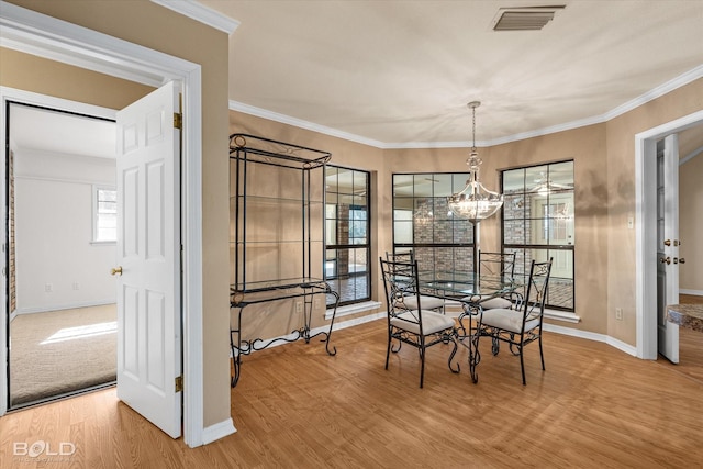 dining area with an inviting chandelier, ornamental molding, and hardwood / wood-style floors