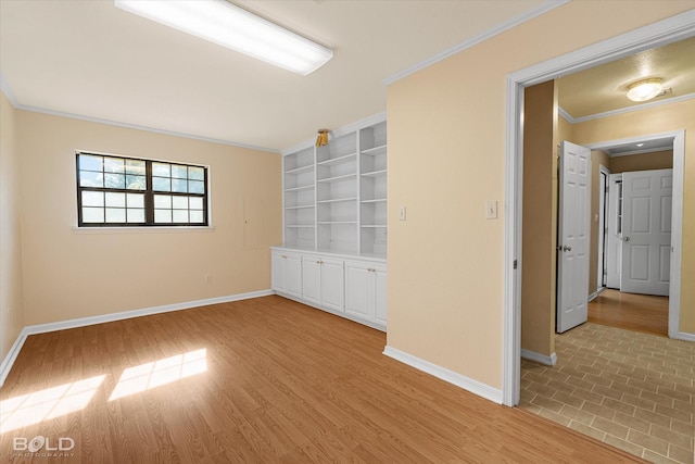 empty room with crown molding, light wood-type flooring, and built in shelves