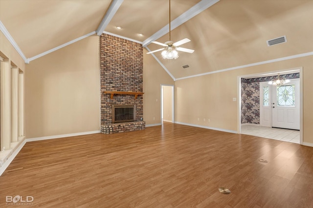 unfurnished living room featuring ornamental molding, ceiling fan with notable chandelier, a fireplace, vaulted ceiling with beams, and light hardwood / wood-style floors