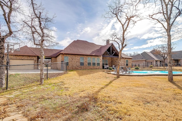 rear view of property with a fenced in pool and a yard