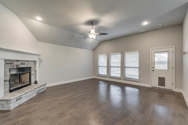 unfurnished living room featuring lofted ceiling, a stone fireplace, dark wood-type flooring, and ceiling fan