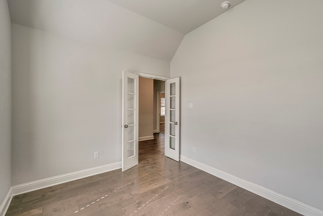 empty room featuring vaulted ceiling, dark hardwood / wood-style flooring, and french doors