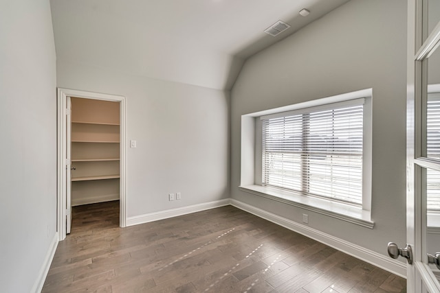 spare room with dark hardwood / wood-style floors and vaulted ceiling