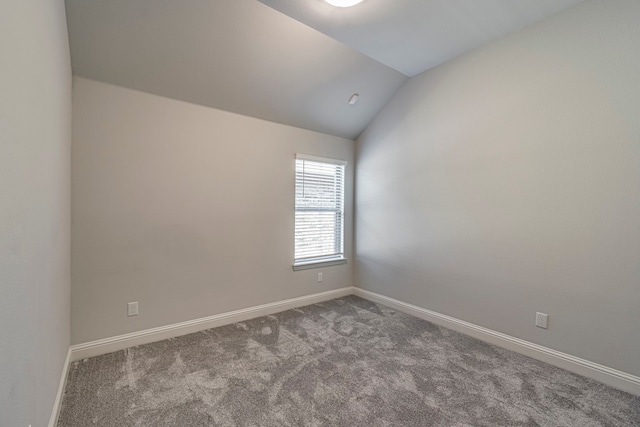 carpeted spare room with vaulted ceiling