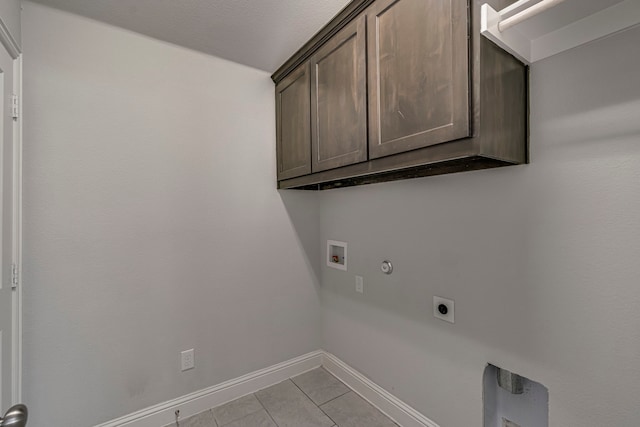 clothes washing area with gas dryer hookup, cabinets, light tile patterned floors, hookup for a washing machine, and hookup for an electric dryer