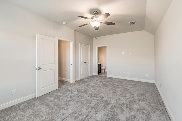 unfurnished bedroom with ceiling fan, carpet, ensuite bathroom, and lofted ceiling