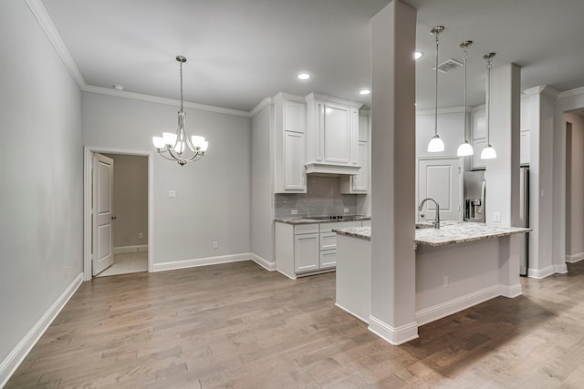 kitchen with light stone counters, ornamental molding, a center island with sink, light hardwood / wood-style floors, and white cabinetry