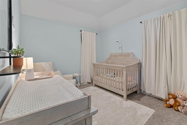 carpeted bedroom with a nursery area and lofted ceiling