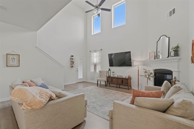 living room featuring a high ceiling, light wood-type flooring, and ceiling fan