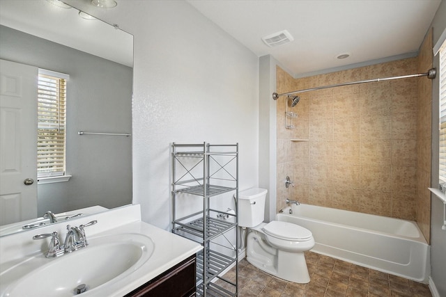 full bathroom featuring vanity, tiled shower / bath combo, and toilet