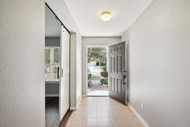 foyer entrance with a barn door and light tile patterned floors