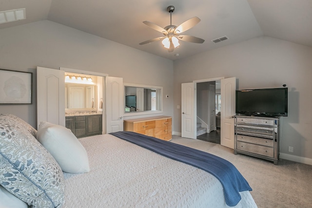 bedroom with ceiling fan, vaulted ceiling, light colored carpet, and ensuite bath