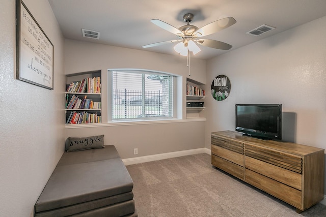 sitting room featuring ceiling fan, carpet floors, and built in shelves