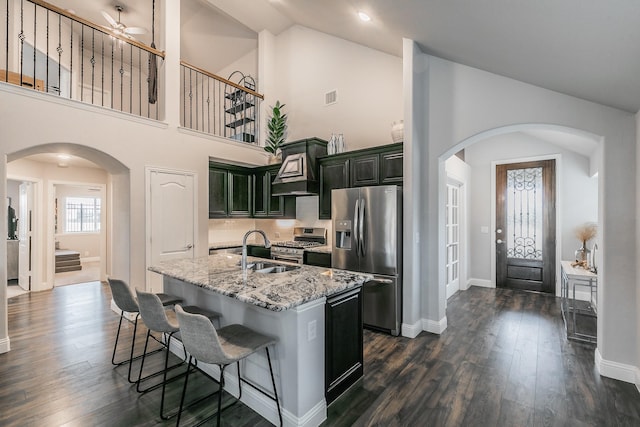 kitchen featuring light stone countertops, sink, stainless steel appliances, dark hardwood / wood-style floors, and an island with sink