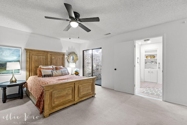 carpeted bedroom with ceiling fan, connected bathroom, and a textured ceiling