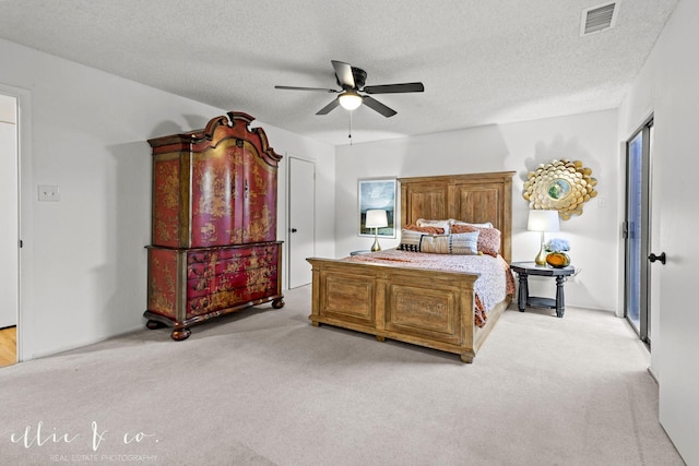 bedroom featuring ceiling fan, light colored carpet, and a textured ceiling