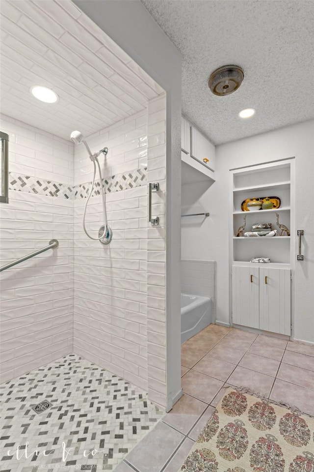 bathroom with a textured ceiling, tile patterned floors, and tiled shower