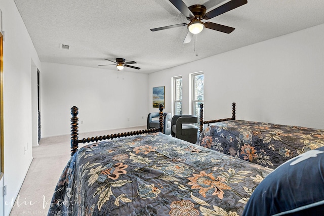 bedroom with ceiling fan, light colored carpet, and a textured ceiling