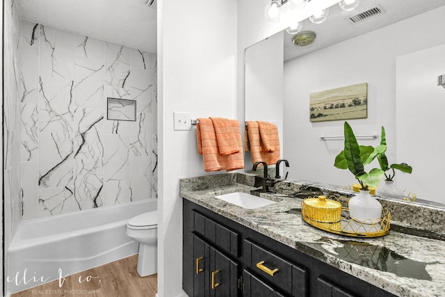 full bathroom with vanity, tiled shower / bath combo, wood-type flooring, and toilet