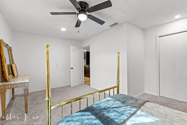 bedroom featuring a closet, ceiling fan, a textured ceiling, and light carpet