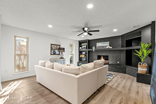 living room with a fireplace, light hardwood / wood-style floors, and a textured ceiling